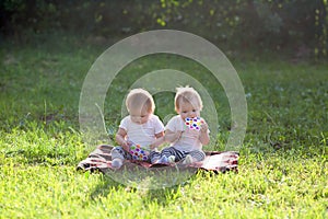 Twin children sit in a city park on a summer day