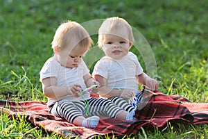 Twin children sit in a city park on a summer day