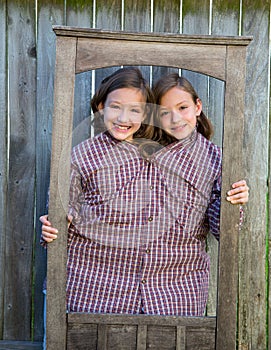 Dvojča dievčatá ozdobný oblečený hore predstierať byť siamský v rámik 