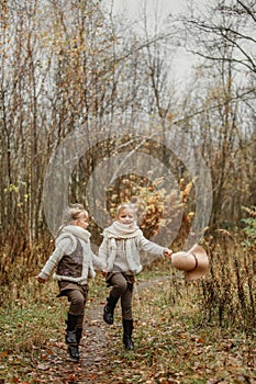 Twin girls play in the autumn park, throw their hats up