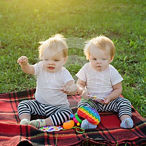 Twin girls play with bright toys on blanket