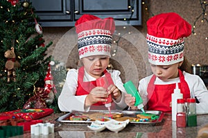 Twin girls in red making Christmas cookies