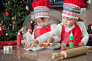 Twin girls in red making Christmas cookies