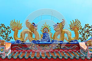 Twin golden chinese dragon on top roof for exterior decoration on blue sky, holy place chinese temple