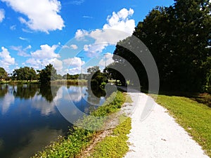 Twin Lakes Park in Sarasota Florida under a bright sunny blue sky with white fluffy clouds a lake and trees