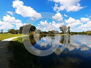 Twin Lakes Park in Sarasota Florida under a bright sunny blue sky with white fluffy clouds a lake and trees
