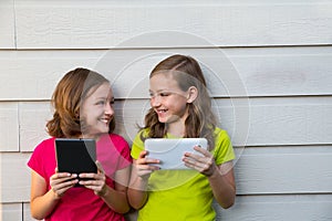 Twin sister girls playing with tablet pc happy on white wall