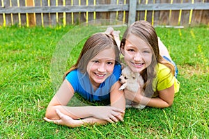 Twin sister kid girls and puppy dog lying in lawn