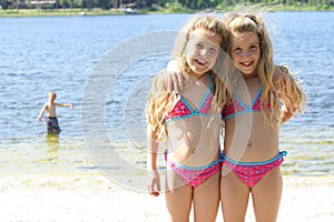 Twin sisters in bathing suits at the lake