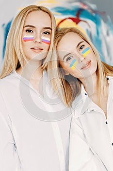 Twin sisters with flags of Russia and Ukraine. Flags are painted on the girls' faces.