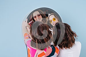 Twin sisters hold a mirror and we see their reflection