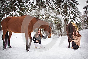 Twin sisters and horse in the winter forest