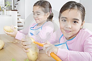 Twin Sisters Peeling Potatoes in Kitchen