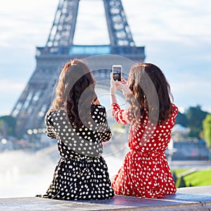 Twin sisters taking selfie near the Eiffel tower in Paris