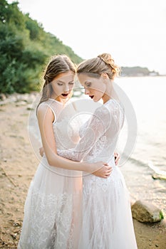 Twin sisters in wedding dress on the seashore