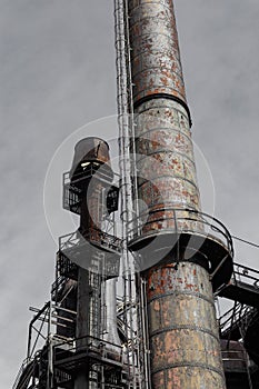 Twin smokestacks with rust patina, riveted metal, industrial site