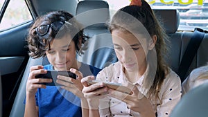 Twins brother and sister use the phone while traveling in the car