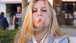 Twins girls friends having fun on evening broadway and Chewing bubble gum. The sister ruined a gum bubble