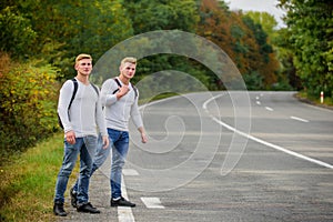Twins men at edge of road nature background. Try to stop some car. Reason people pick up hitchhikers. Missed their bus