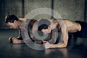 Twins muscular men working out with dumbbell. tattooed arm