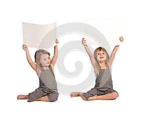 Twins in rompers holding blank paper sheets