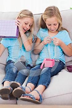 Twins unwrapping birthday gift sitting on a couch
