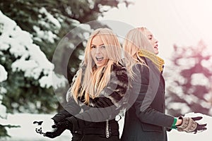 Twins women playing snowballs in forest on snow park. Girls with smiling outdoors on winter day. Christmas and new year