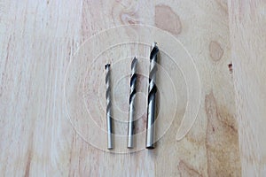 Twist drill bits on wooden background