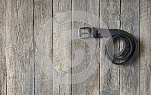 Twisted black male leather belt on a wooden background