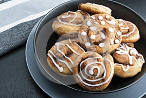 Twisted buns with cinnamon and icing sugar on a black background