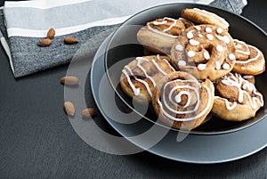 Twisted buns with cinnamon and icing sugar on a black background