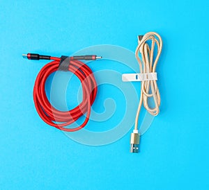 Twisted cable for charging mobile devices in a red and golden textile wrapper