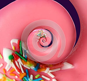 Twisted donut with strawberry icing and sprinkles on purple background, spiral effect