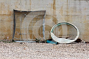 Twisted old highly used metal manhole frame filled with strong wire mesh next to cracked broken plastic manhole cover