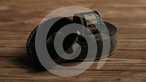 Twisted into rolls of old 35mm blank film negatives on a wooden table in the dark close up.