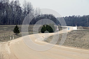 Twisting winding meandering gravel road in weald with signs near forest wood