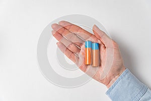 Two AA alkaline battery lying on women`s palm. Generic accumulator on white background photo