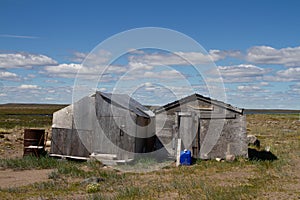 Two abandoned buildings on a bare arctic summer landscape