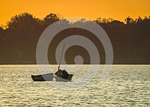 Two abandoned fishing boats in the middle of a lake at sunset