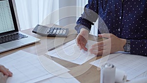 Two accountants are shaking hands after counting taxes at a wooden desk in the office. Teamwork and agreement in