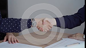 Two accountants are shaking hands after counting taxes at a wooden desk in office. Teamwork in business audit and