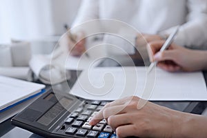 Two accountants use a calculator and laptop computer for counting taxes or revenue balance. Business, audit, and taxes