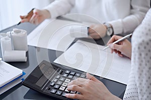 Two accountants use a calculator and laptop computer for counting taxes or revenue balance. Business, audit, and taxes