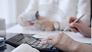 Two accountants use a calculator and laptop computer for counting taxes or revenue balance. Business, audit, and taxes