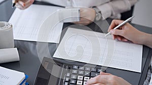 Two accountants use a calculator and laptop computer for counting taxes or revenue balance. Business, audit, and taxes