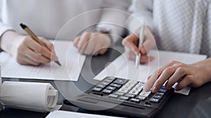 Two accountants use a calculator and laptop computer for counting taxes or revenue balance. Business, audit, and taxes