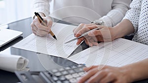Two accountants use a calculator and laptop computer for counting taxes or revenue balance. Business, audit, and taxes
