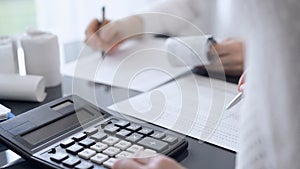 Two accountants use a calculator and laptop computer for counting taxes or revenue balance. Business, audit, and taxes