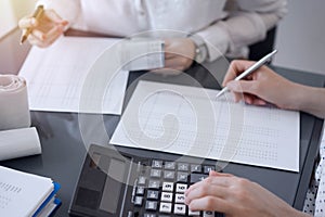 Two accountants use a calculator and laptop computer for counting taxes or revenue balance. Business, audit, and taxes