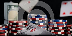 Two aces in the foreground, surrounded by chips, for playing poker and banknotes, on a black background